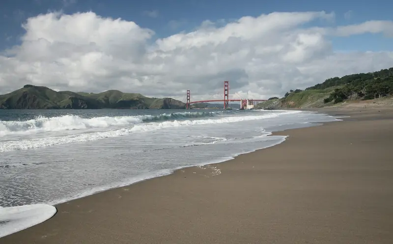 Photo of waves at Baker Beach with the Golden Gate Bridge in the distance